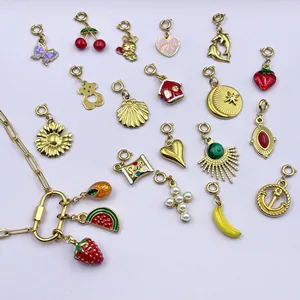 Variedad de dijes de acero inoxidable dorado con esmalte en formas de corazón y frutas