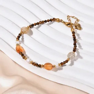 Detail of tiger eye and agate beaded bracelet with a stainless steel heart charm.