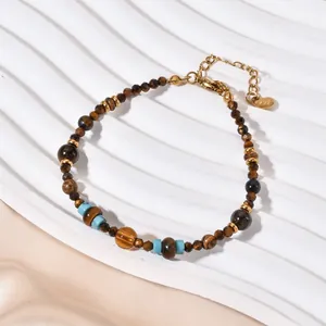 Detail of ethnic style bracelet with tiger eye and agate stones on white wavy background