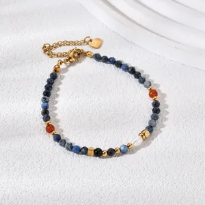 Detail of beaded bracelet with natural pearl, blue stones and gold heart charm.