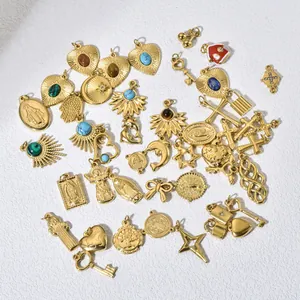Primer plano de dijes de acero de titanio dorado con piedras de colores para joyería DIY.