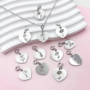 Gros plan sur des pendentifs cœur en acier inoxydable avec gravures de fleurs de naissance.