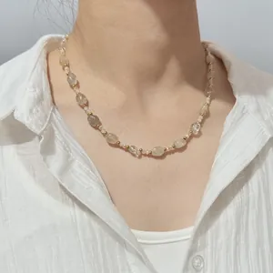 Close-up of a natural crystal beaded necklace worn by a model in a white shirt.
