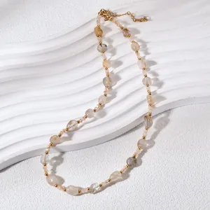 Close-up view of a natural crystal stone necklace with gold beads on a wave display