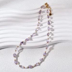 Detailed view of natural purple crystal and white beaded necklace on white platform.