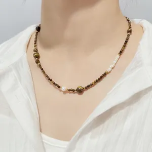 Detailed view of handcrafted natural stone beaded necklace with tiger's eye and white shell beads.