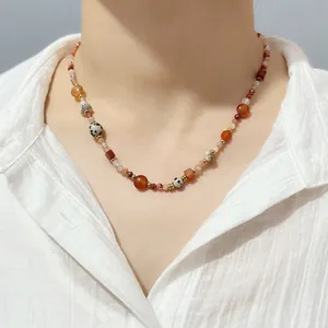 Close-up of colorful natural stone beaded necklace worn on neck with white shirt.