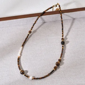 Macro view of handcrafted natural tiger's eye and pearl beaded necklace on fabric.