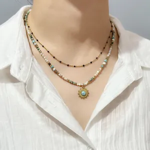 Detail shot of a bohemian beaded necklace featuring a turquoise sun pendant on a white shirt