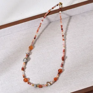 Detailed view of the multi-colored natural stone beaded necklace on a textured tray.