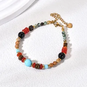 Macro detail of colorful natural stone beaded bracelet with a golden heart-shaped charm