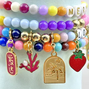 Close-up of stainless steel fruit and letter charms on colorful beaded bracelets