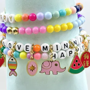 Macro view of colorful stainless steel enamel fruit and animal charms on DIY beaded bracelets