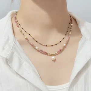 Close-up detail of an elegant layered beaded necklace with a pearl pendant on a model