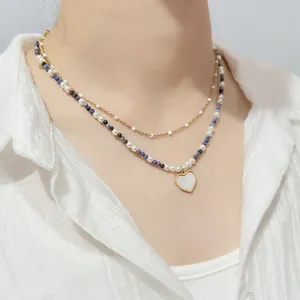 Close-up detail of elegant double-layered beaded necklace with gold heart pendant on model