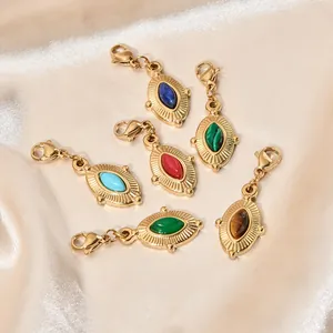 Vue détaillée des pendentifs vintage en acier inoxydable doré avec diverses pierres.