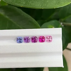 Vibrant gradient lab-grown cushion cut colored gemstones presented on white display tray