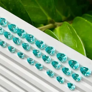 Pierres précieuses Paraiba YAG de synthèse taille poire sur plateau d'exposition blanc