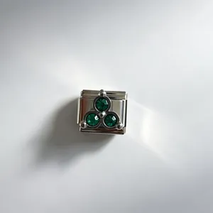 Gros plan d'un maillon de bracelet italien en acier inoxydable avec trois pierres vertes.