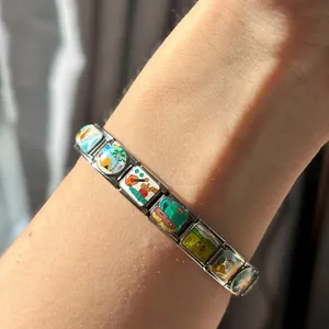 Nahaufnahme eines italienischen Bettelarmbands mit bunten Emaille-Modulen am Handgelenk