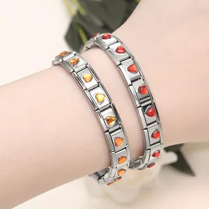 Gros plan de deux bracelets modulables italiens en acier inoxydable avec zircons cœur colorés.