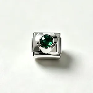 Macro detail view of a polished stainless steel Italian charm with a green heart crystal