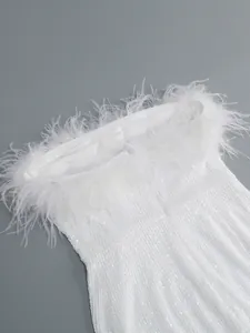 Detalle de un vestido de tubo con lentejuelas blancas y un elegante adorno de plumas de avestruz.