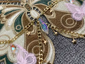 Dettaglio ravvicinato di un accessorio a farfalla ricamato con catene d'oro e stelle