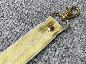 Dettaglio macro che mostra il cinturino metallico dorato e la chiusura a moschettone.