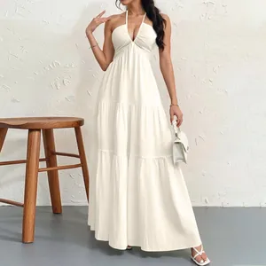 Elegant white halter tiered maxi dress detail presented with a textured wall background