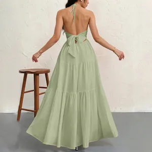Back view of a light green halter maxi dress with an open back and bow tie detail