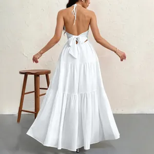 Back view of a white halter neck maxi dress featuring a large bow and tiered skirt