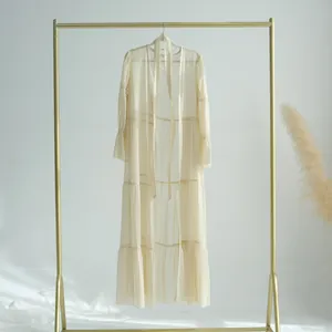 Élégante robe longue à volants en mousseline crème sur un portant à vêtements doré