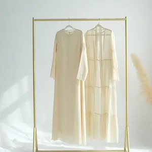 Élégant ensemble deux pièces en mousseline de soie beige avec cardigan long sur un portique