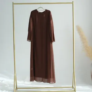 Élégante robe deux pièces en mousseline plissée marron sur un portant doré sophistiqué.