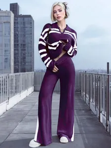 Stylisches lila gestricktes Set mit Polokragen und weitem Bein auf einer Dachterrasse.