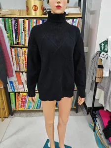 Detail of a black turtleneck sweater with diamond knit pattern shown on a mannequin.