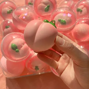 Close-up of a slow-rising peach squishy toy held in hand with capsule background