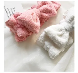 Vista dettagliata di fasce per capelli con fiocco in morbido peluche rosa e bianco.