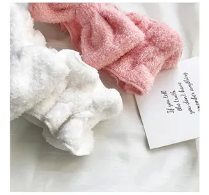 Dettaglio ravvicinato della morbida texture delle fasce in peluche con fiocco rosa e bianco