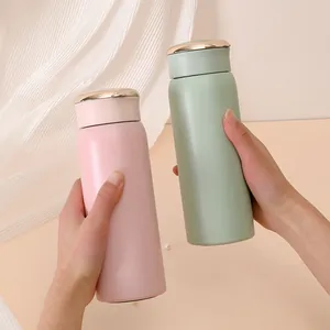 Twee matte roze en muntgroene vacuümgeïsoleerde waterflessen in handen
