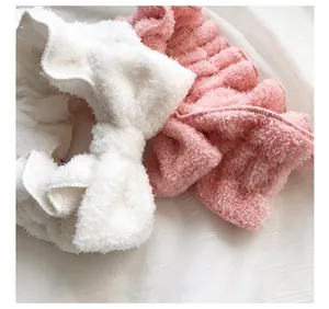 Primo piano di fasce per capelli con fiocco di peluche bianche e rosa.
