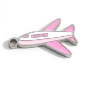 Detalle macro de un dije de avión en esmalte rosa y blanco de acero inoxidable para DIY.