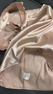 Dettaglio ravvicinato di un top halter in raso rosa con trama liscia ed etichetta di lavaggio