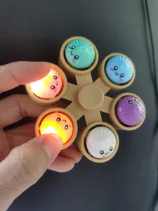 Macro view of the cute bun fidget spinner keychain lighting up during hand pressing