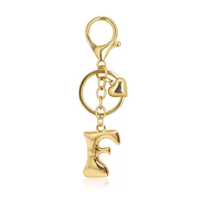Close-up of a golden bubble letter F keychain with heart charm and lobster clasp