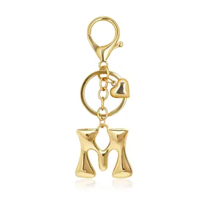 Close-up of a stylish golden bubble letter M keychain featuring a heart charm and clasp