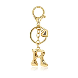 Close-up view of a golden bubble letter R keychain with lobster clasp and heart charm