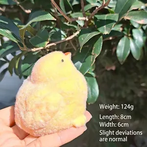 Yellow fuzzy chick squeeze toy held in hand showing soft plush texture and compact size
