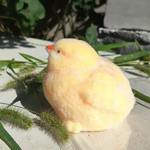 Close-up of a realistic yellow plush chick toy in a natural sunlit outdoor setting